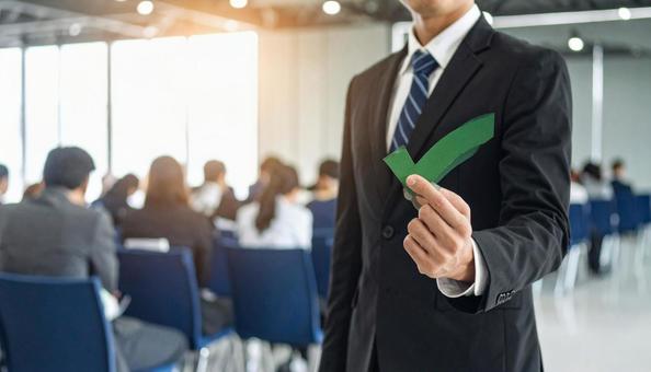 チェックマークを片手に持つビジネスマンの写真