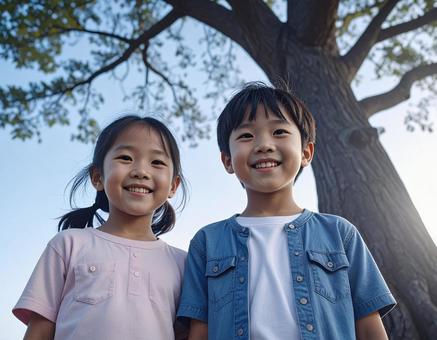 大きな樹の下に立つ子供たちの写真