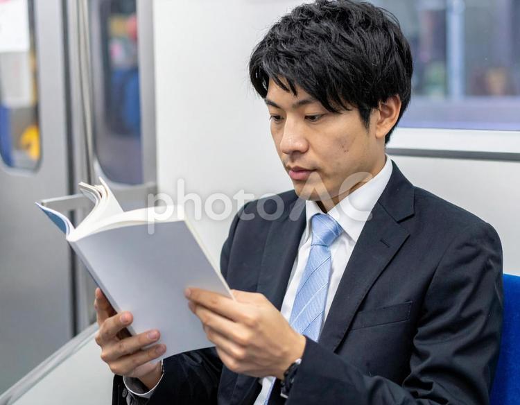 電車の中で本を読むビジネスマン男性 電車,本,ビジネスマンの写真素材