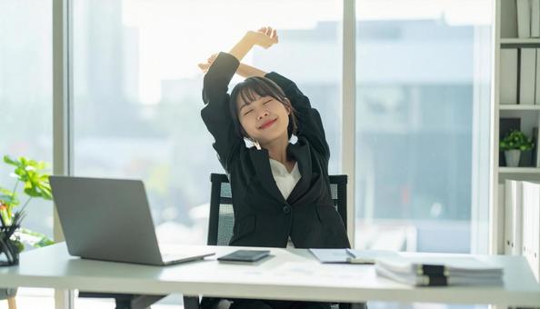 仕事が終わり達成感で背伸びをする社員の写真