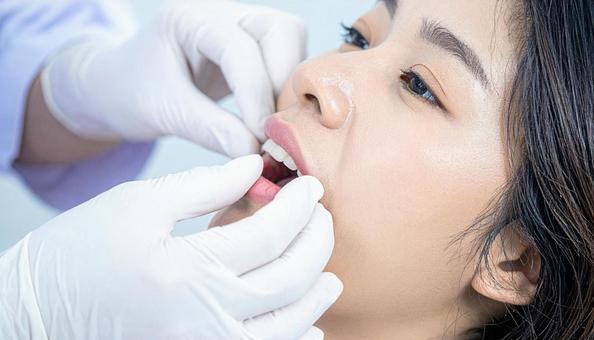 歯医者で患者の歯肉を指で歯肉マッサージの写真