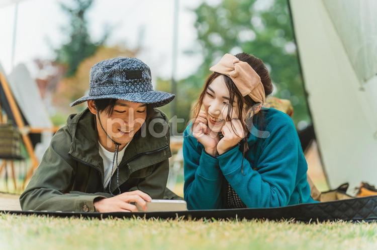 スマホで動画を見るカップル（キャンプ） キャンプ,スマホ,カップルの写真素材
