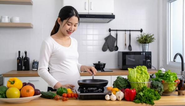キッチンで料理をする妊婦 キッチンで料理をする妊婦の写真