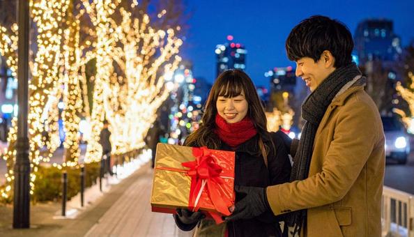ギフトを手にする男女とイルミネーション ギフトを手にする男女とイルミネーションの写真