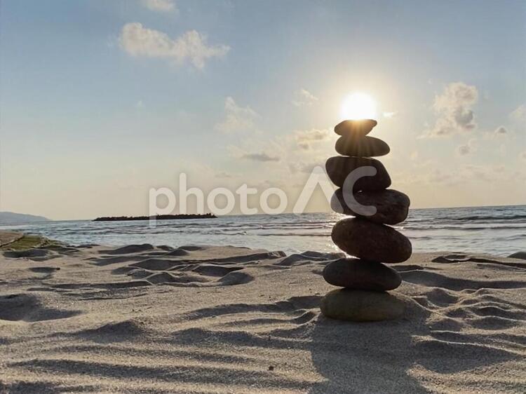 砂浜に石が積んであり太陽と重なっています 砂浜,浜,石の写真素材