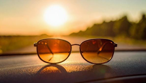 車のダッシュボードに置かれたサングラス 車のダッシュボードに置かれたサングラスの写真