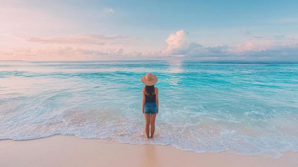 波打ち際で海を眺める女性の後ろ姿 波打ち際で海を眺める女性の後ろ姿の写真