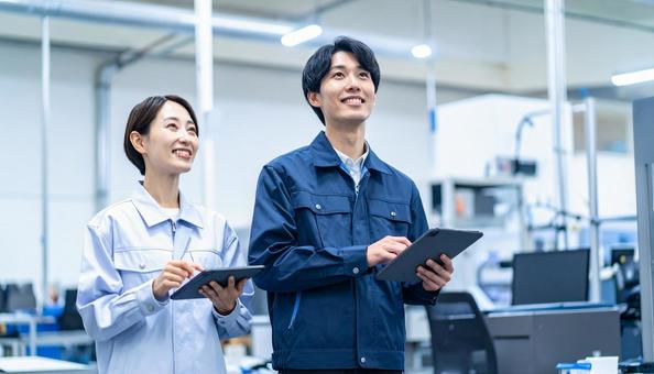 工場でタブレットで製品を検査する作業員 工場でタブレットで製品を検査する作業員の写真