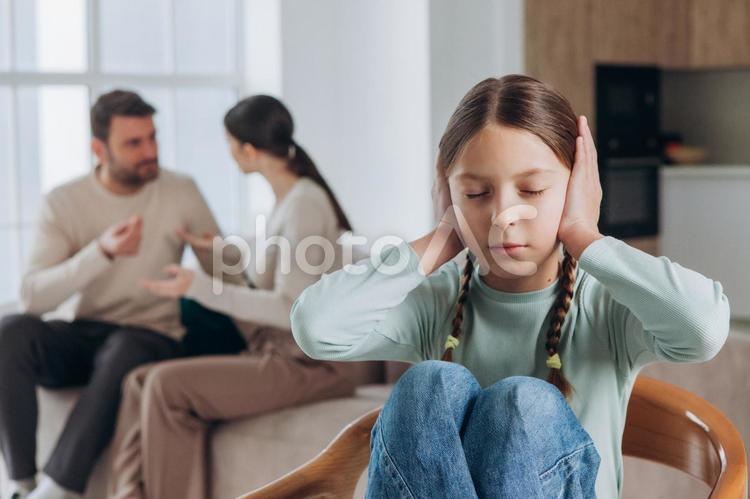 耳を塞ぐ女の子と喧嘩する両親 親子,女の子,両親の写真素材