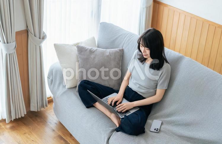 ソファに座ってパソコンを使う女性 女性,ソファ,パソコンの写真素材
