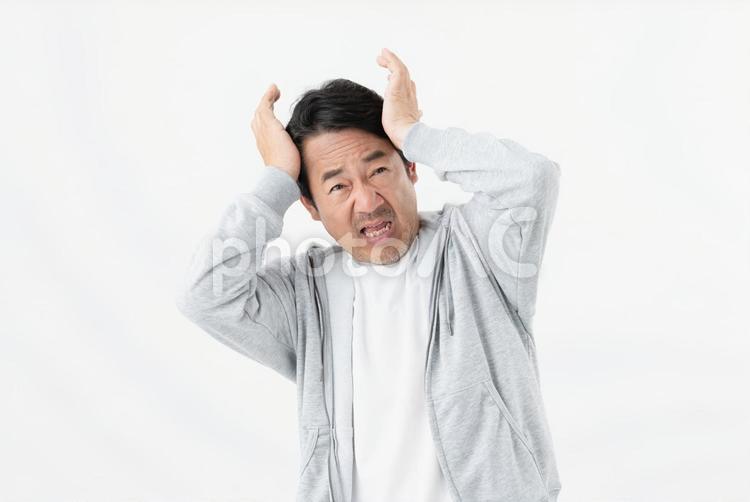 頭を抱えるミドルの男性 頭痛,痛い,悩みの写真素材