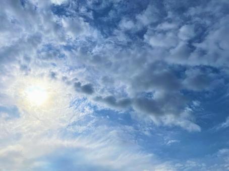 明るく光る太陽と雲の多い空 明るく光る太陽と雲の多い空の写真