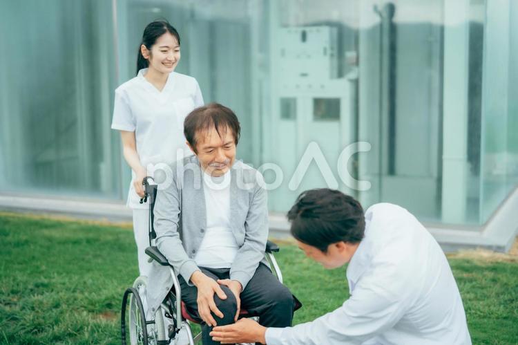 車椅子に乗った患者と医療スタッフ（3人） 車椅子,患者,病院の写真素材