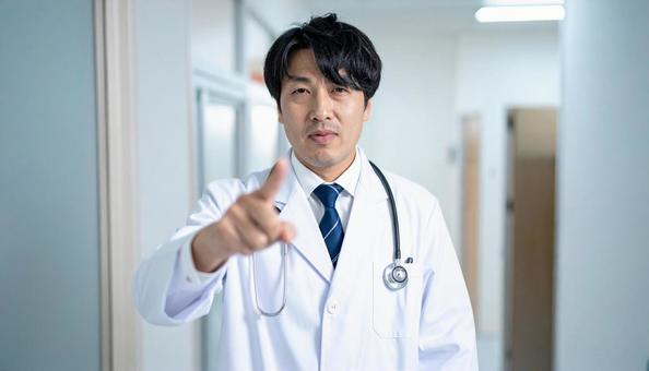 病院内で正面を指さす医師の写真