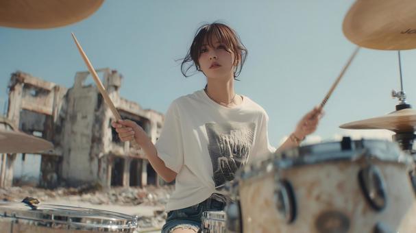 廃工場を背景に力強くドラムを叩く女性 廃工場を背景に力強くドラムを叩く女性の写真