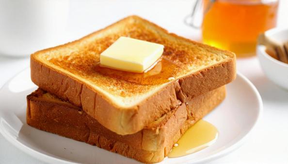 バターが乗ったトーストにかけるはちみつの写真