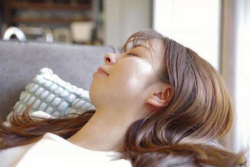 ソファでゆったりと横になる若い女性 お昼寝,休息,リラックスの写真素材