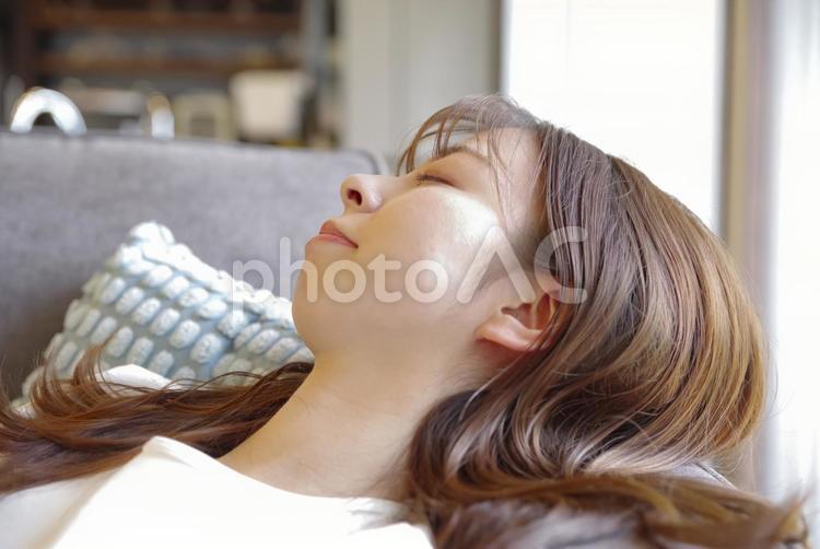 ソファでゆったりと横になる若い女性 お昼寝,休息,リラックスの写真素材