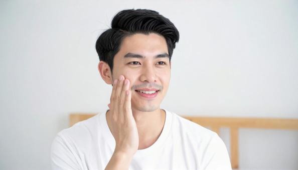 頬を触る白いTシャツの男性モデル 頬を触る白いTシャツの男性モデルの写真