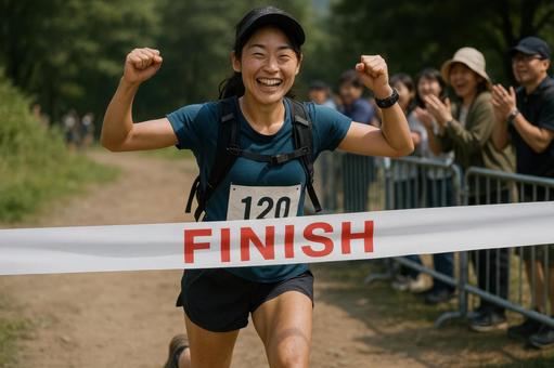 ゴールテープを切る笑顔の女性ランナー ゴールテープを切る笑顔の女性ランナーの写真