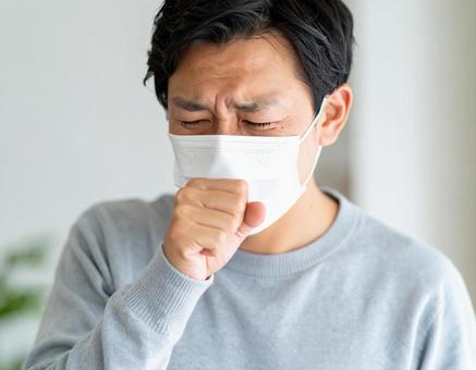 マスクを着用して咳をするの男性 マスクを着用して咳をするの男性の写真