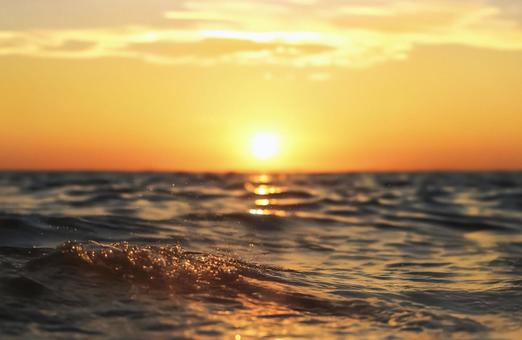オレンジ色の太陽が照らす夏の海面の風景 オレンジ色の太陽が照らす夏の海面の風景の写真