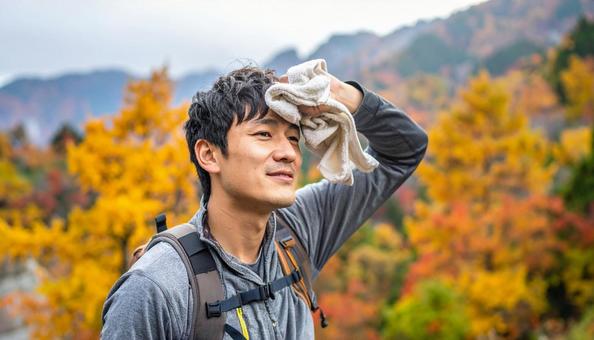 汗をタオルで拭く秋の山登りする日本人男性 汗をタオルで拭く秋の山登りする日本人男性の写真
