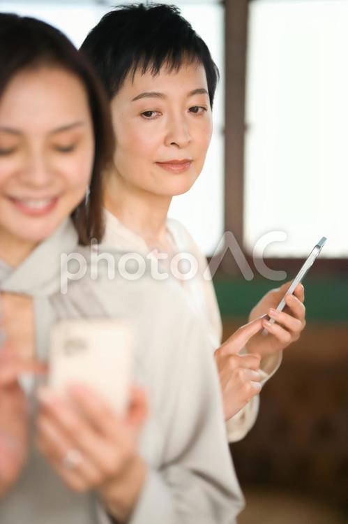 携帯を操作する女性と覗く女性 女性,主婦,携帯の写真素材