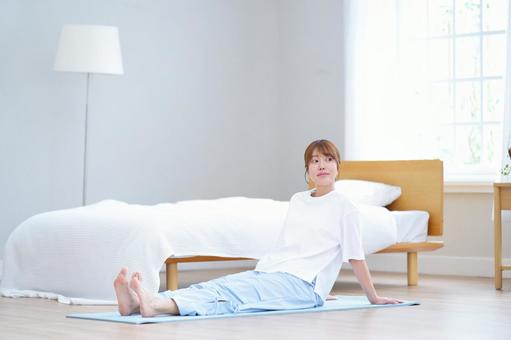 足を伸ばしヨガマットに座る女性の写真