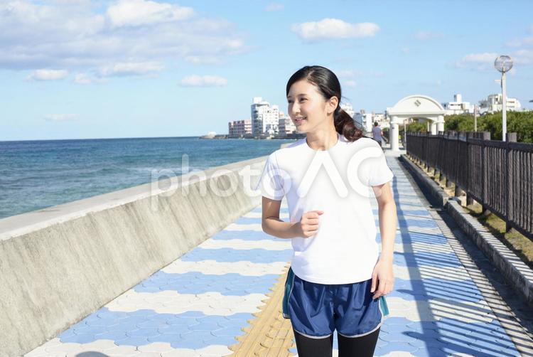 海岸でジョギングを楽しむ女性 女性,女,沖縄の写真素材