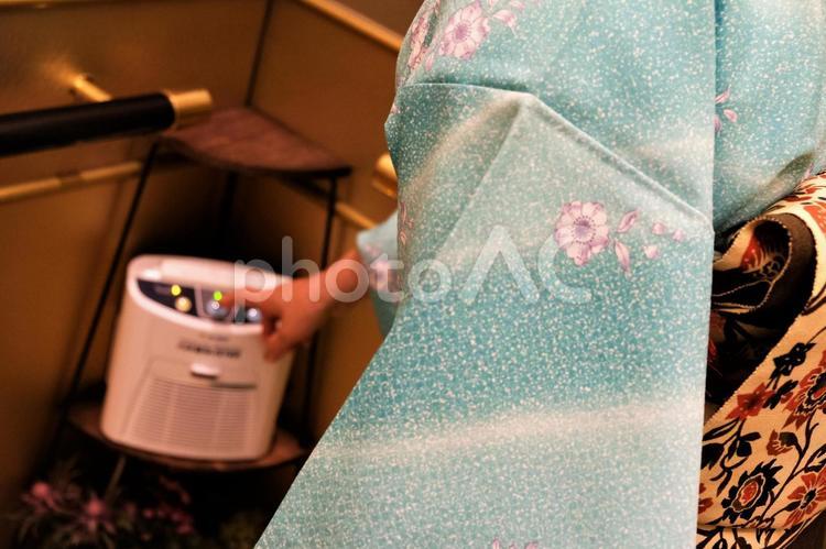 エレベーターの中で空気清浄機のボタンを押そうとしている着物の女性 エレベーター,屋内,着物の写真素材