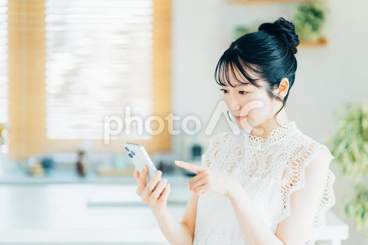 部屋でスマホを操作する若い女性。 女性,スマートフォン,スマホの写真素材