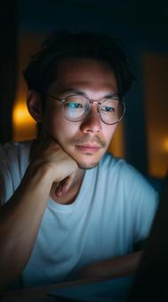 夜の部屋で手を頬に当てて思考する眼鏡男性 夜の部屋で手を頬に当てて思考する眼鏡男性の写真