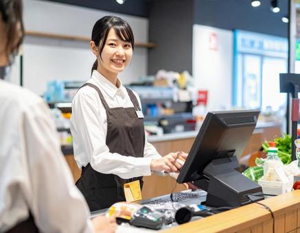 スーパーで笑顔でレジ業務をする女性店員 スーパーで笑顔でレジ業務をする女性店員の写真