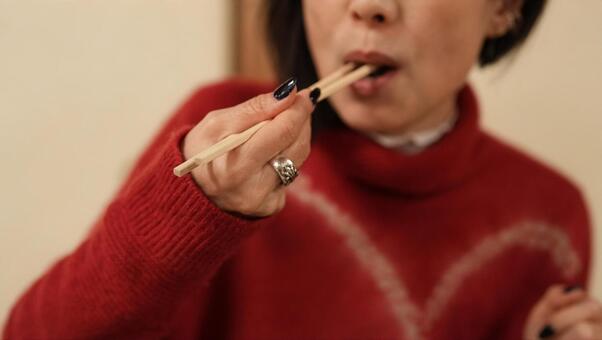 鰻を食べる女性 女性,赤いセーター,手の写真素材