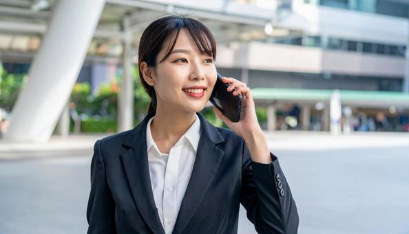 オフィス街で通話するビジネスウーマン オフィス街で通話するビジネスウーマンの写真