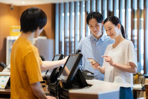 ショッピングをしてモバイル決済をする女性 モバイル決済,ショッピング,カップルの写真素材