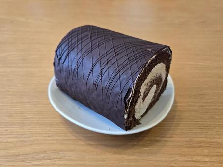 白いお皿に乗ったチョコレートロールケーキ 白いお皿に乗ったチョコレートロールケーキの写真