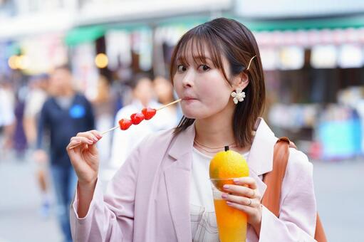 いちご飴を食べながらカメラを見る女性 女性,オレンジジュース,食べるの写真素材