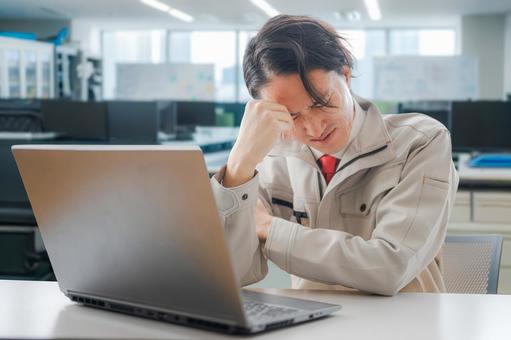 頭を抱える作業員 パソコン,作業着,作業員の写真素材