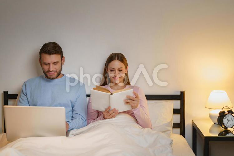 微笑んでパソコンする男性と読書する女性 男性,女性,もたれるの写真素材