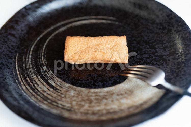 黒い皿に焼き菓子一つ⑦ 焼き菓子,フィナンシェ,黒い皿の写真素材