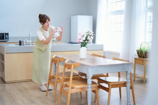 テーブルの上の花を撮影する女性 女性,花,花瓶の写真素材