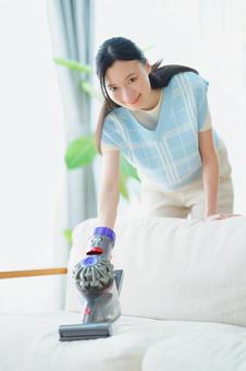 カメラ目線で掃除機を持つ女性 女性,掃除機,ソファの写真素材