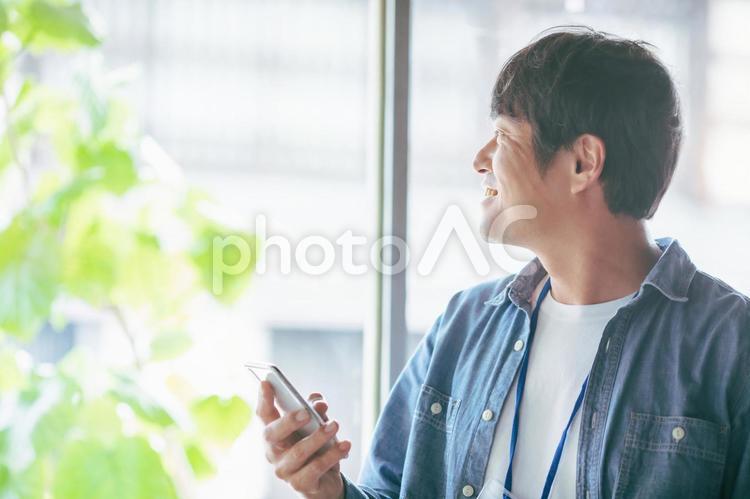 服装自由な会社でスマホを使う会社員 スマホ,検索,スマートフォンの写真素材