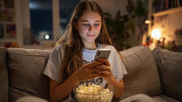 映画鑑賞中にスマホを見る10代の少女 映画鑑賞中にスマホを見る10代の少女の写真