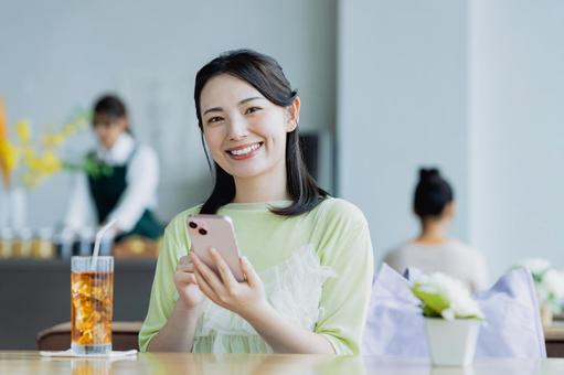 カフェでスマホを使う若い女性 カフェでスマホを使う若い女性 女性,カフェ,笑顔の写真素材