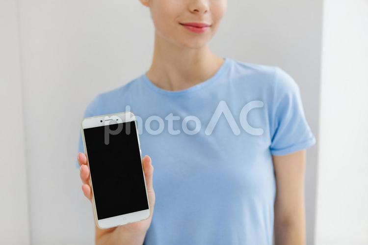 スマホの画面を見せている女性の手元 スマートフォン,持つ,手元の写真素材