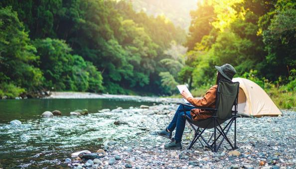 河原でチェアリングをする若い日本人女性の写真