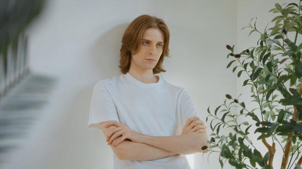 腕組みをして壁にもたれる白いTシャツの男性 男性,外国人,欧米人の写真素材